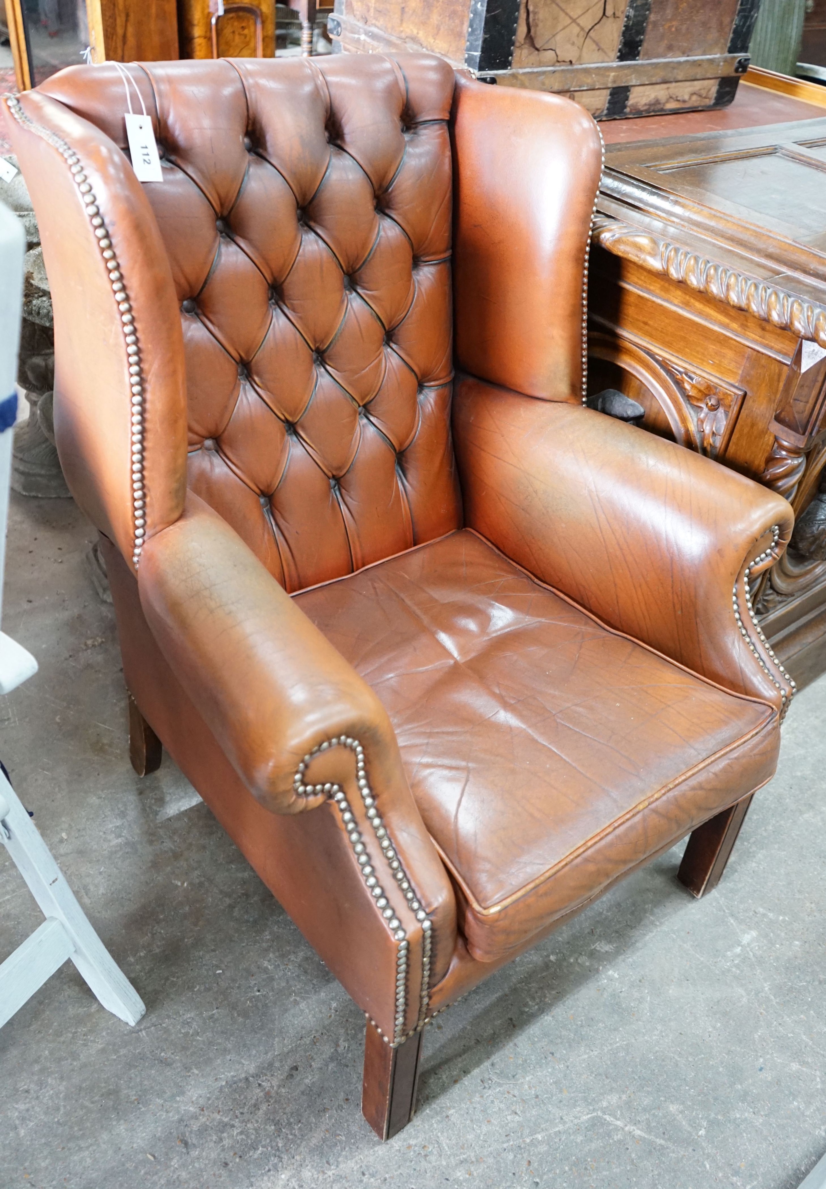 A modern buttoned brown leather wing armchair, width 70cm, depth 76cm, height 96cm